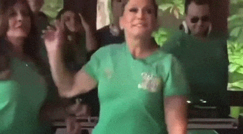Susana Vieira dançando com algumas pessoas de camiseta verde e calça branca.